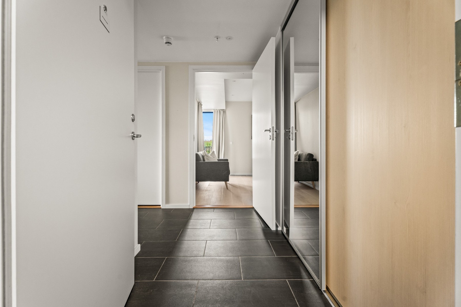 Vel inne gir entreen et godt førsteinntrykk, med downlights, lysegrå vegger og store, mørke fliser på gulvet. Galleribilde