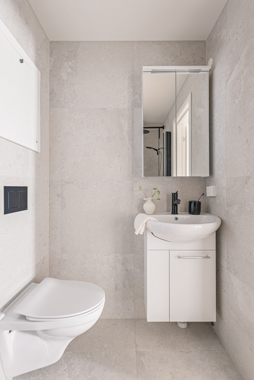 Badet består av heldekkende servant på underskap, speil og belysning, vegghengt toalett og dusj med dusjvegger i herdet glass. Galleribilde