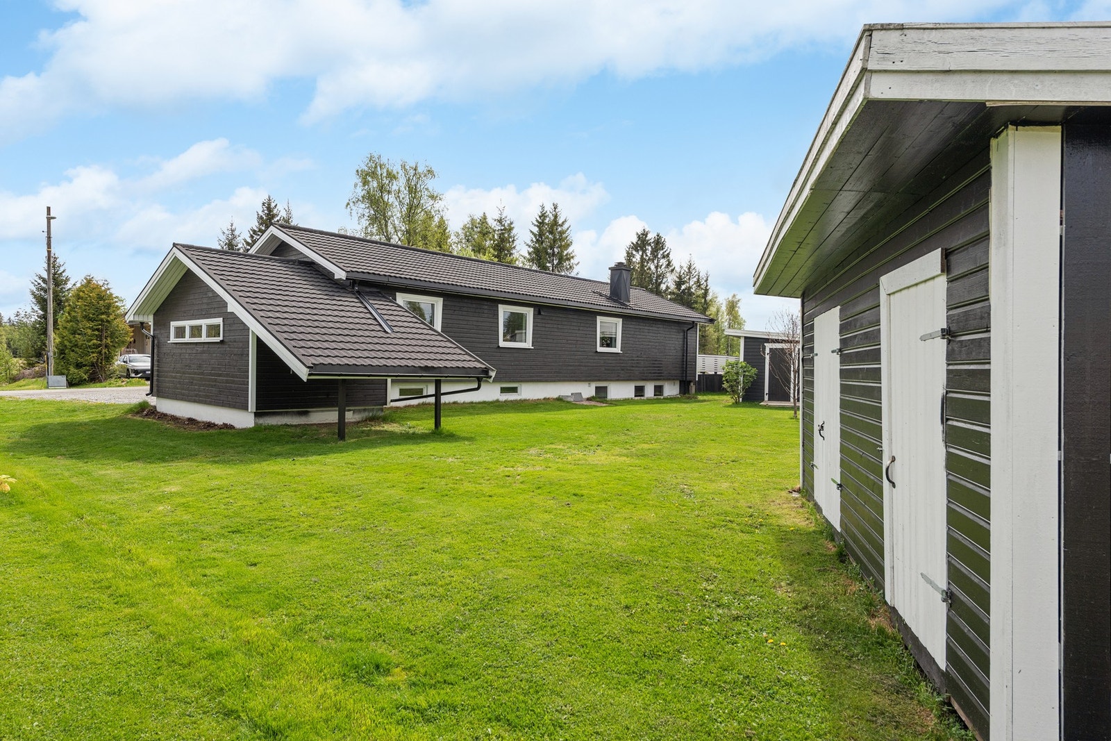 Tomten fremstår som pent opparbeidet med plenarealer, gruset gårdsplass og beplantning. Galleribilde