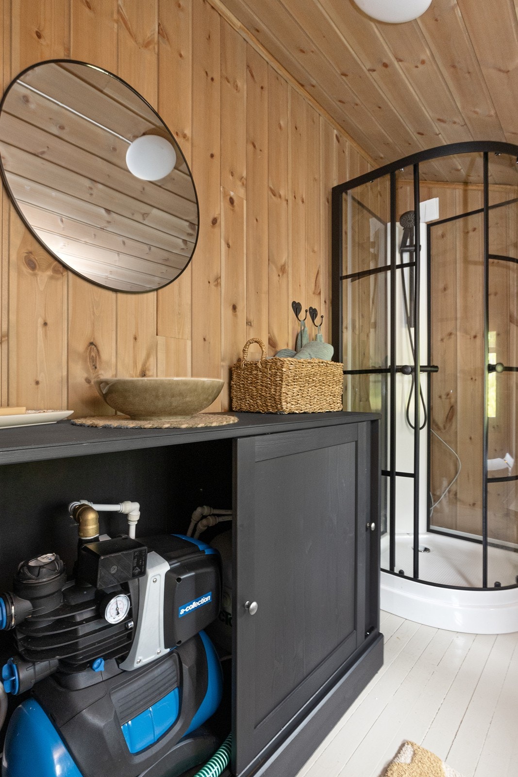 Badet har tregulv og panelvegger, med dusjkabinett og forbrenningstoalett. Galleribilde