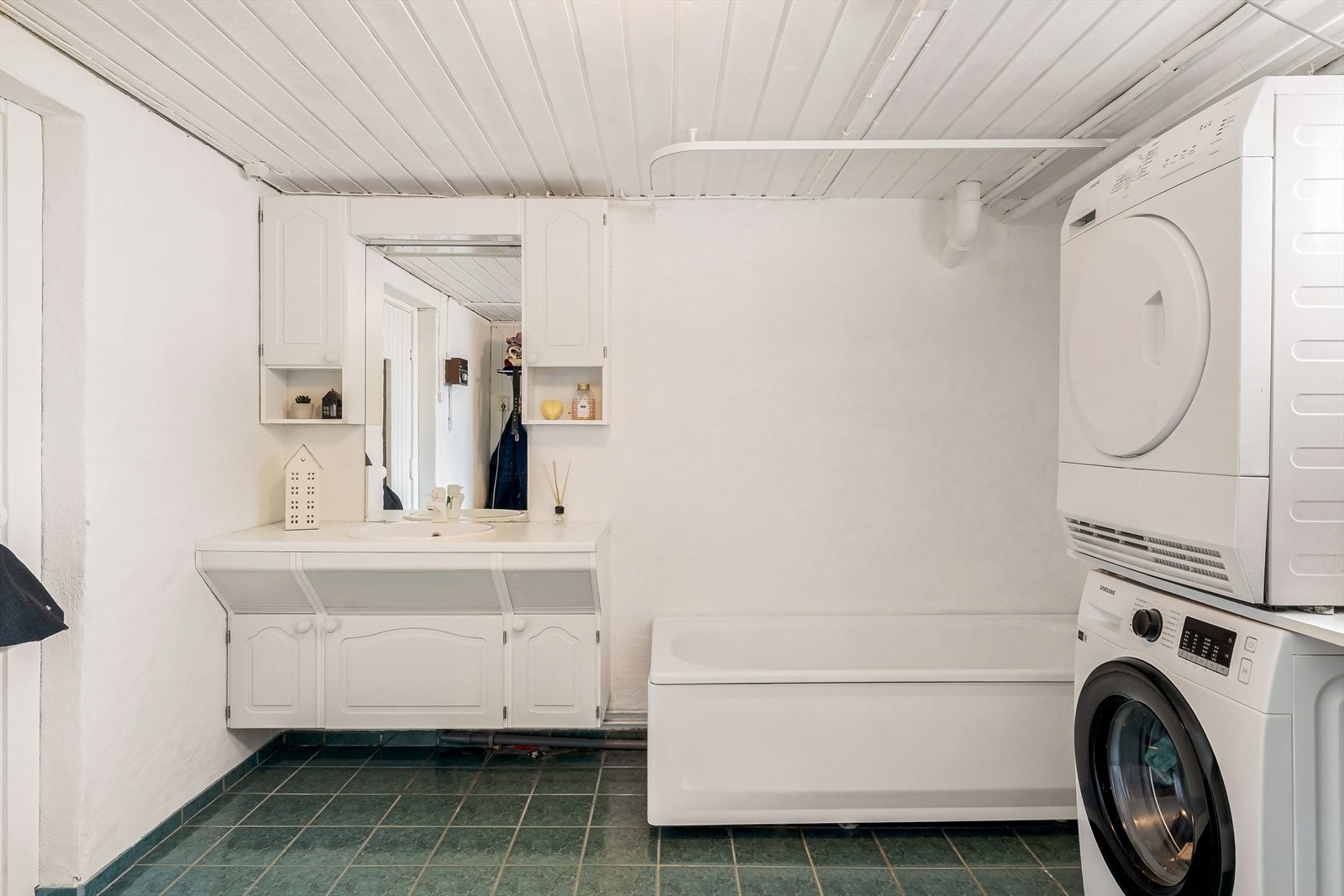 Rommet er utstyrt med badekar, servantinnredning og opplegg for vaskemaskin. Her er også boligens stoppekran. Galleribilde