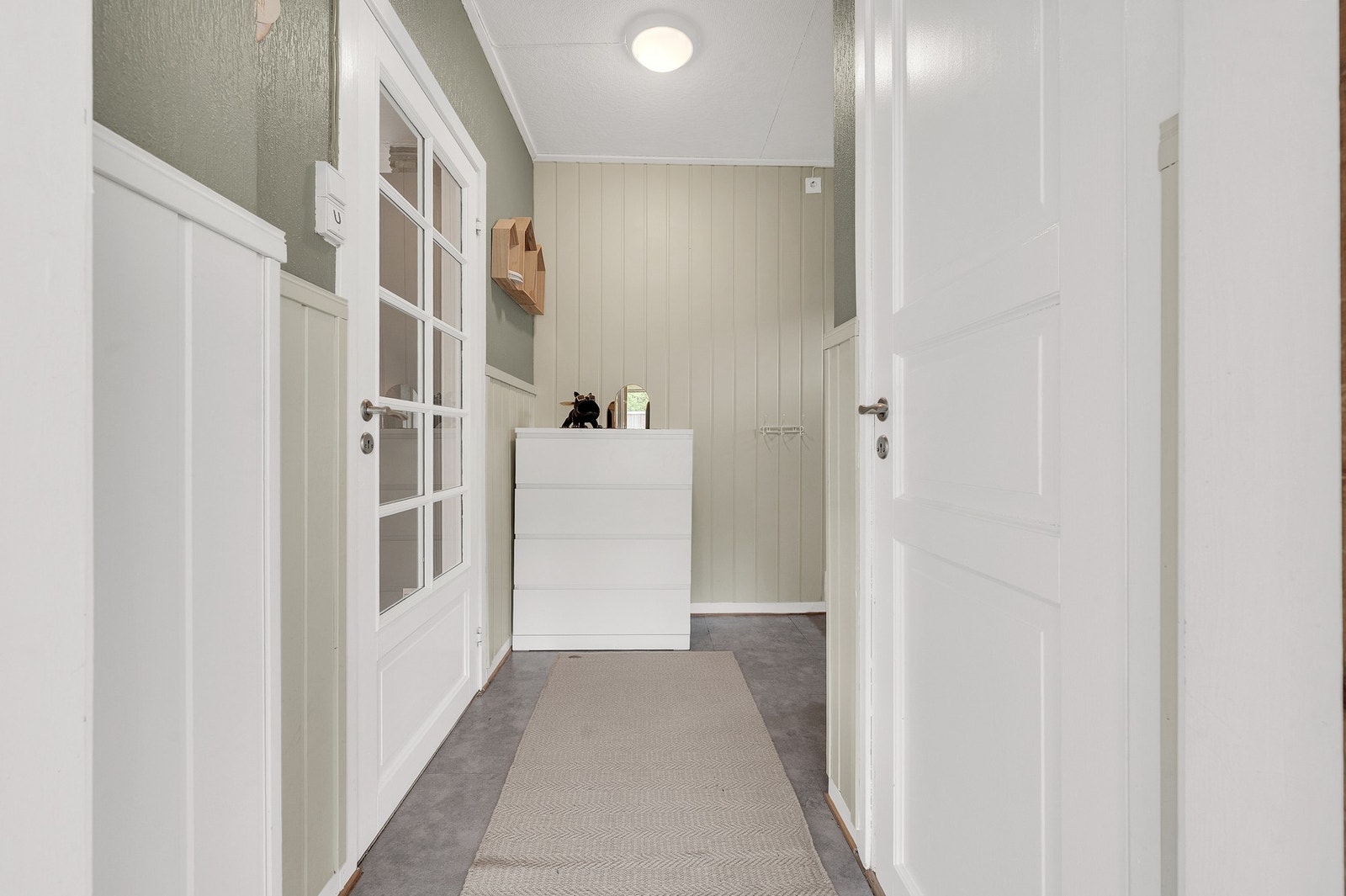 Entré med trapp til loft og kjeller. Veggene har en kombinasjon av malte bygningsplater og panel. Foto: H5 Galleribilde