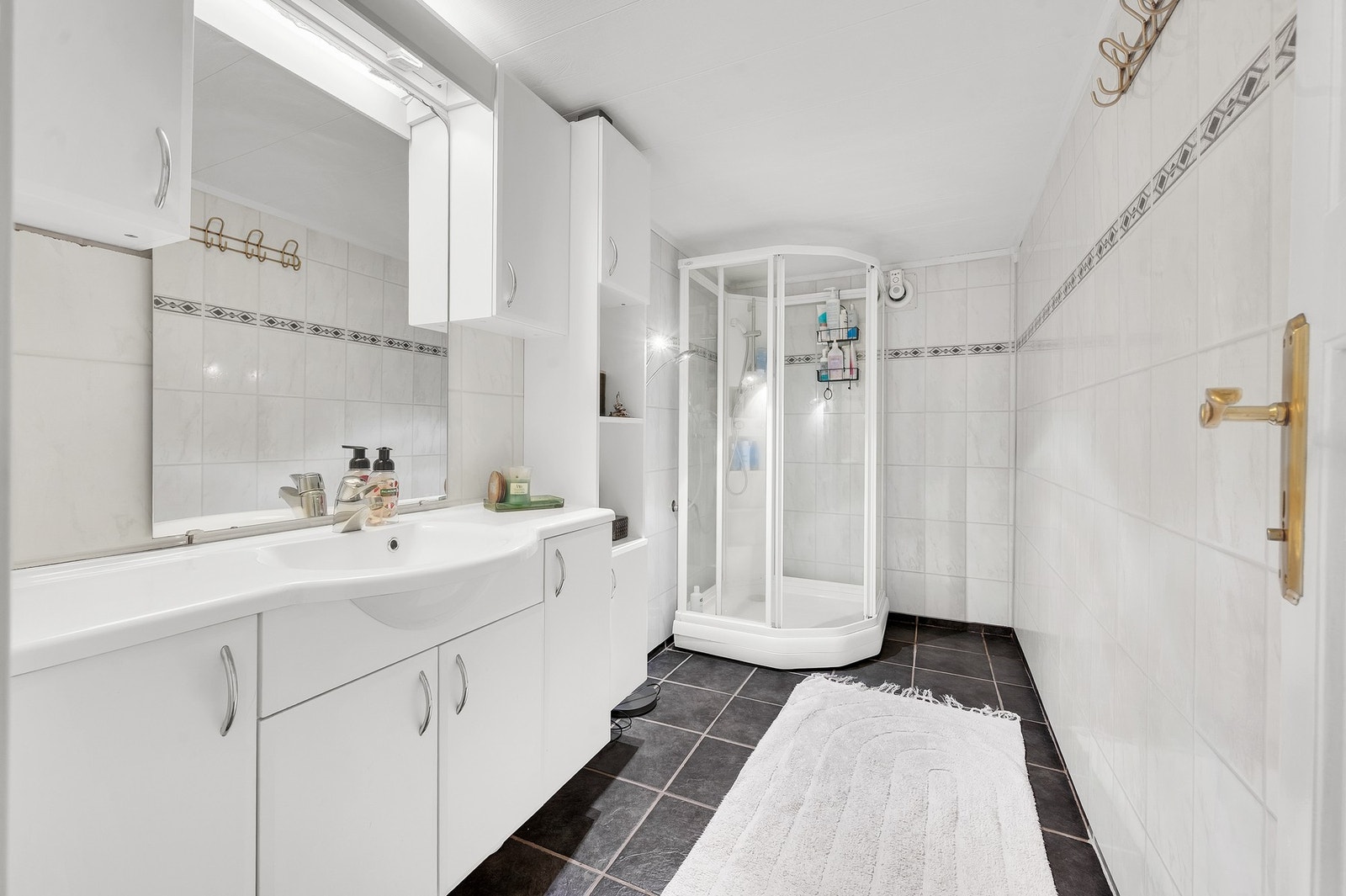 Bad i kjeller med fliser på gulv, våtromsplater på veggene og dusjkabinett. Foto: H5 Galleribilde