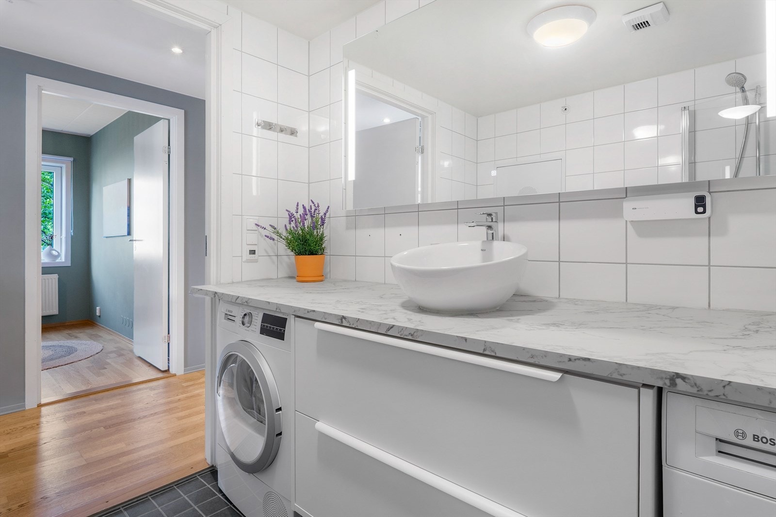 Badet har flislagt gulv med elektriske varmekabler, dusjhjørne og opplegg for vaskemaskin. Tørketrommel og vaskemaskin kan stå igjen om ønskelig Galleribilde