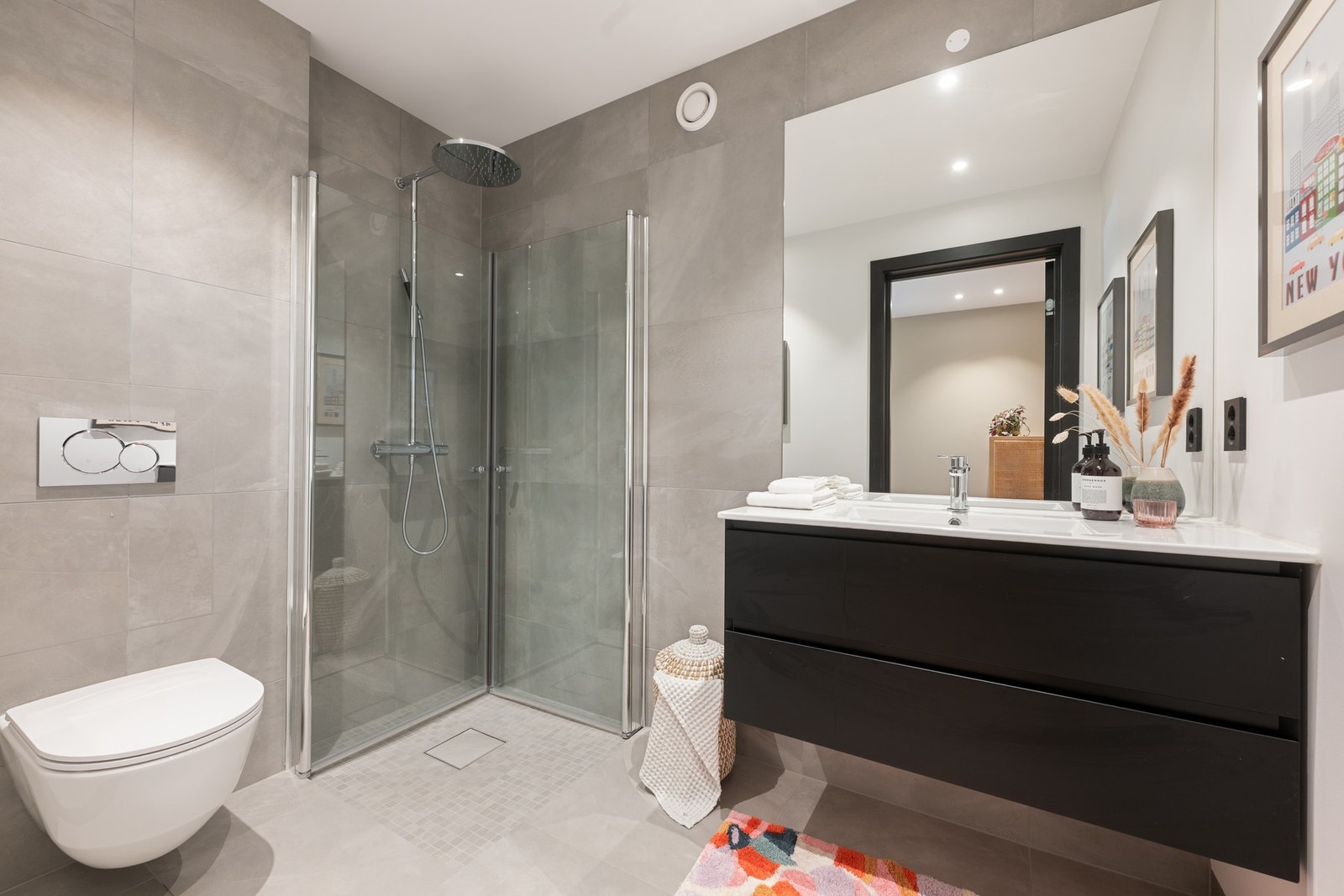 Badet i 1. etasje er lekkert utført med 60x60 fliser, varme i gulvet, vegghengt toalett og dusjsone med mosaikkfliser og innfellbare glassdører. Galleribilde