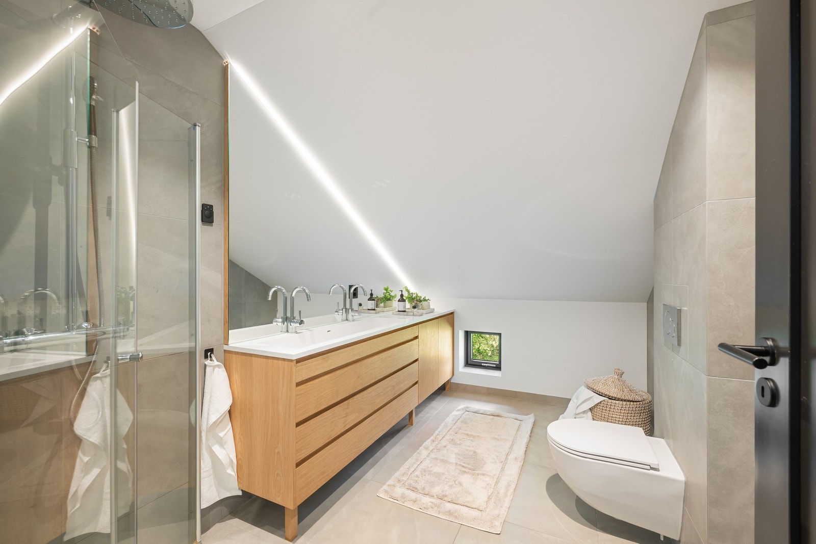 Badet i 3. etasje er romslig og lekkert, med 60x60 fliser, varme i gulvet, vegghengt toalett og en stilren servantløsning med to armaturer. Galleribilde