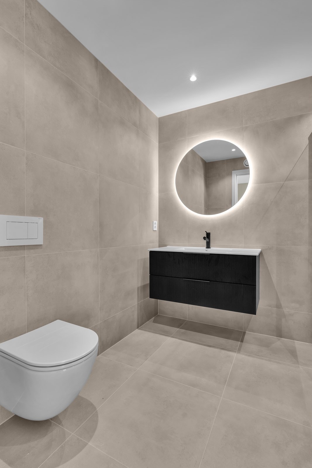Badet er delvis flislagt med store, nøytrale fliser på gulv og vegger. (Illustrasjonsbilde fra tilsvarende bolig) Galleribilde