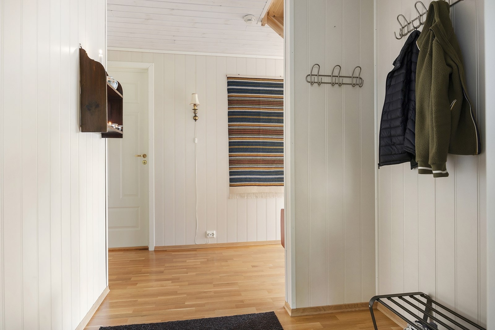 Entré med parkett på gulv. Vegger med MDF-plater og tak med trepanel er gjennomgående i hytta. Galleribilde