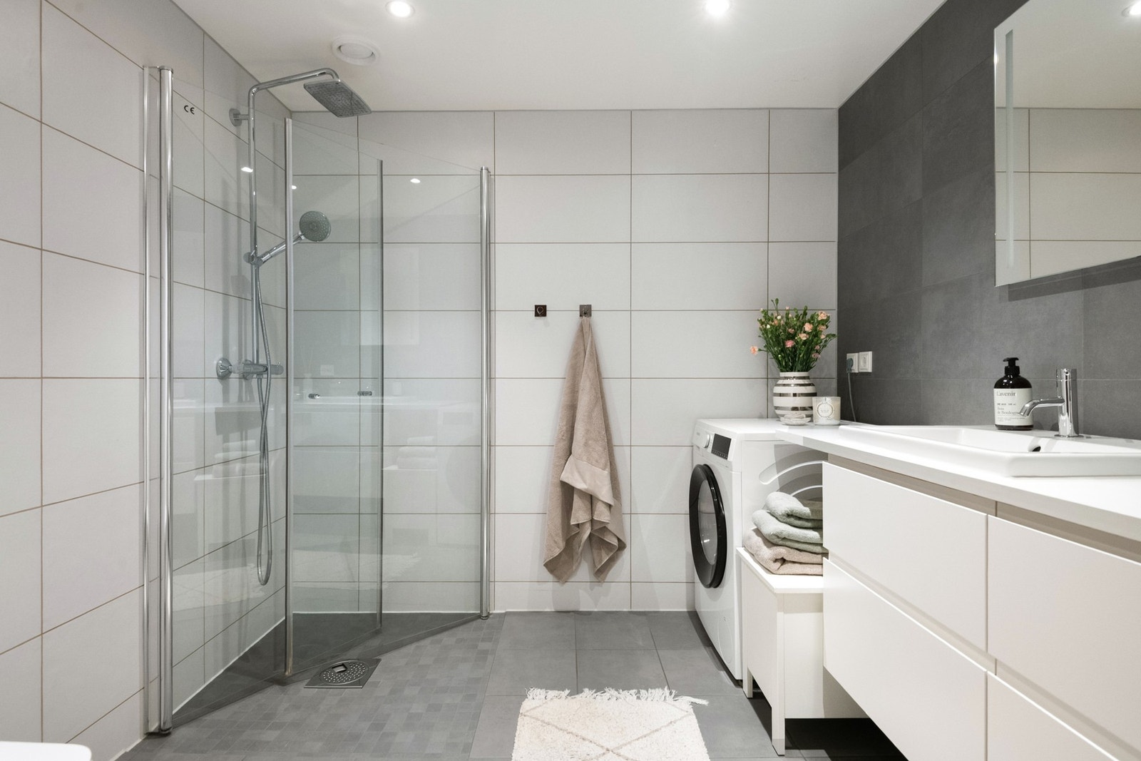 Badet er moderne innredet med flislagte overflater og opplegg for vaskemaskin Galleribilde