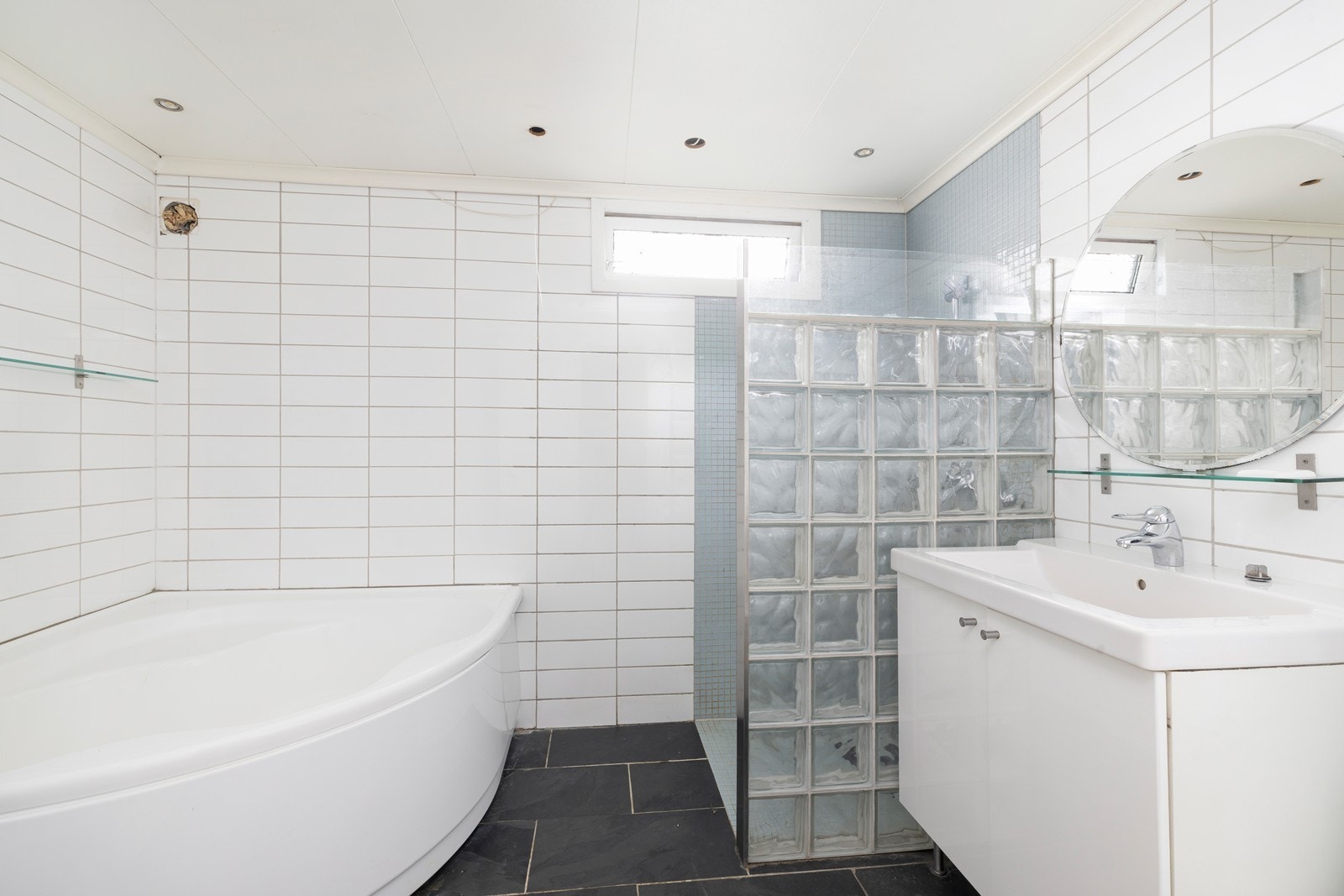 Romslig flislagt bad med varme i gulv. Badet har badekar, dusjhjørne, servant med underskap og toalett. Galleribilde
