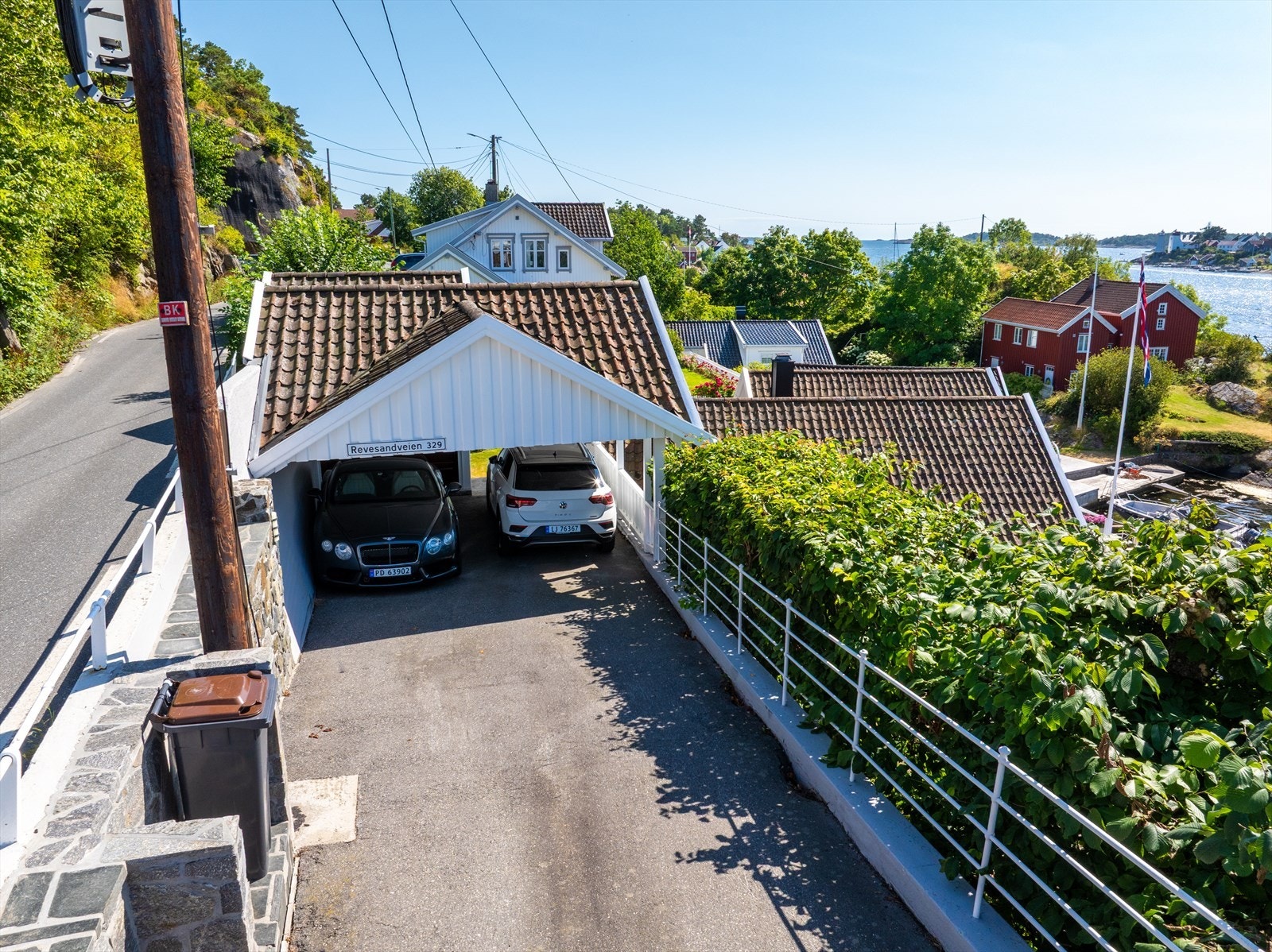 Dels overbygget adkomst parkering i bakkant med asfaltert gårdstun, plass for flere biler med både dobbel carport og garasje. Galleribilde