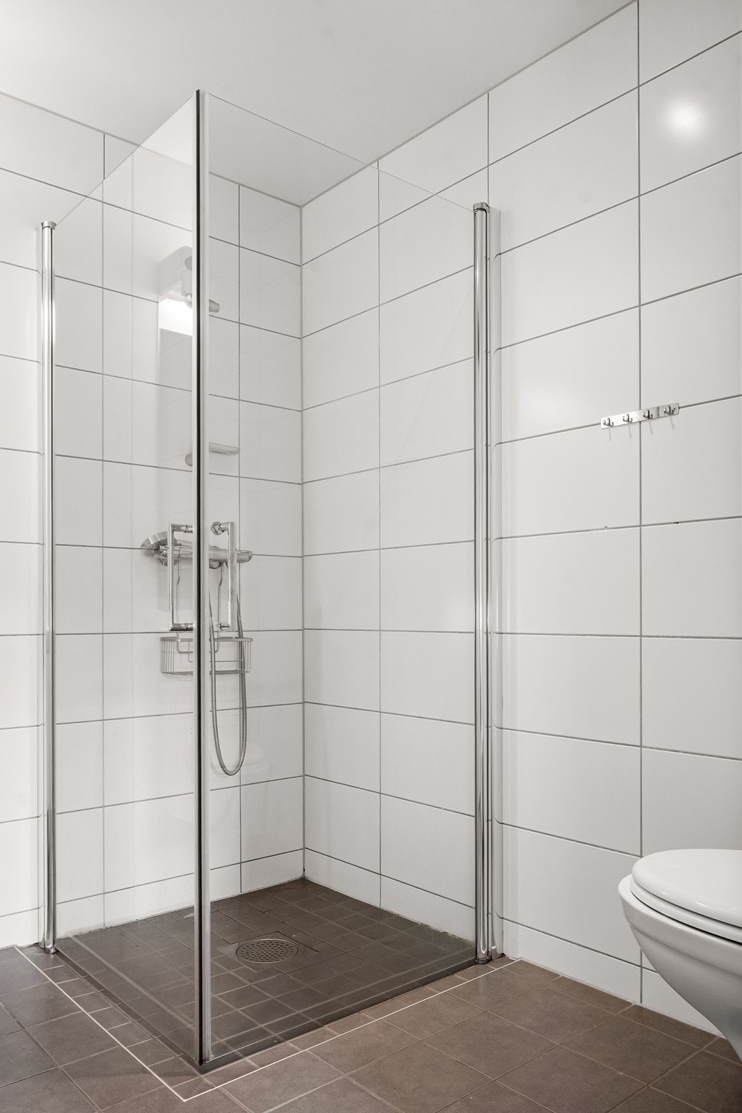 Badet har vannbåren gulvvarme, vegghengt toalett og dusjhjørne med innfellbare glassdører. Galleribilde