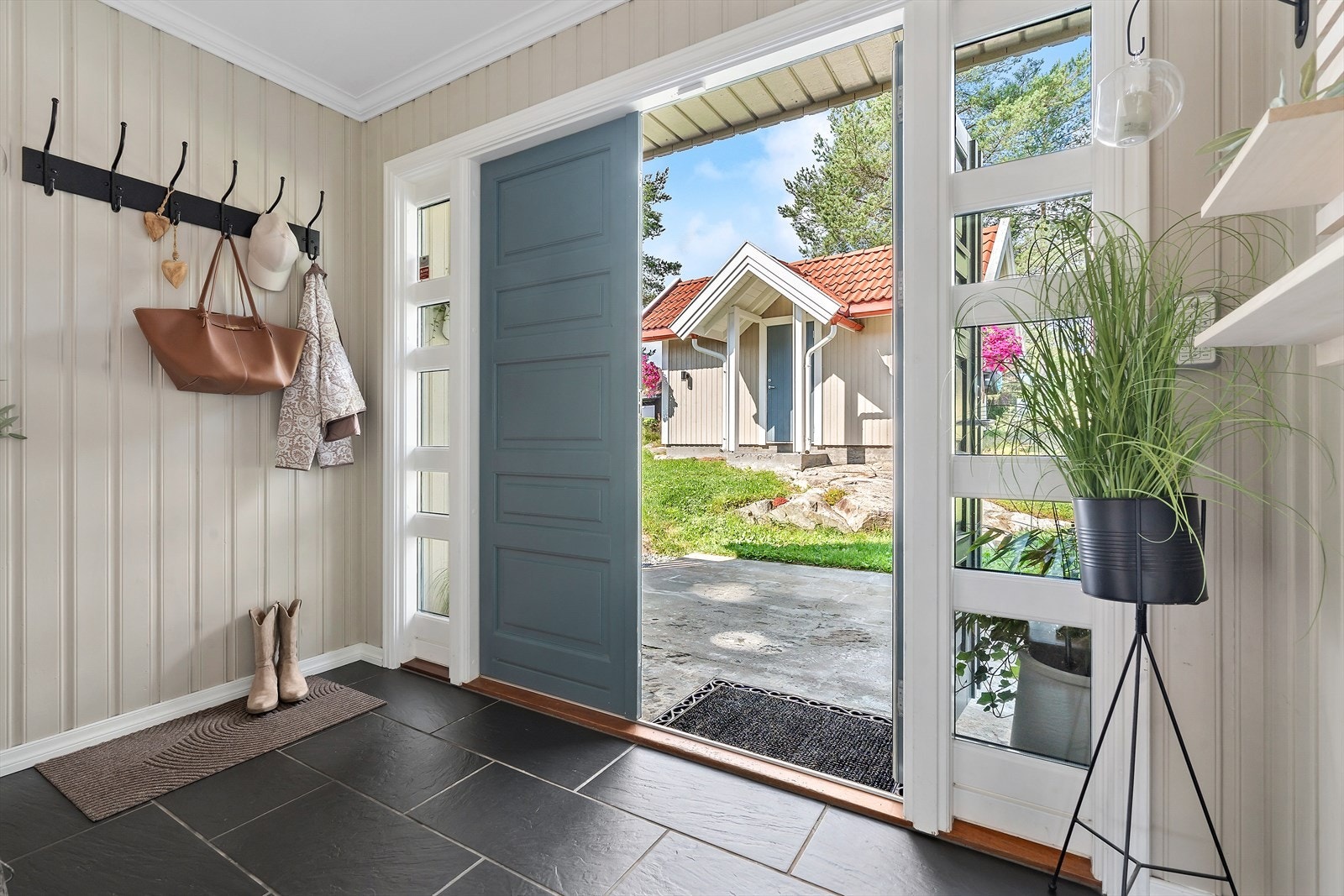 Velkommen inn! Til en lys gang med fliser på gulv. Det er knagger på veggen til å henge fra seg yttertøy. Galleribilde