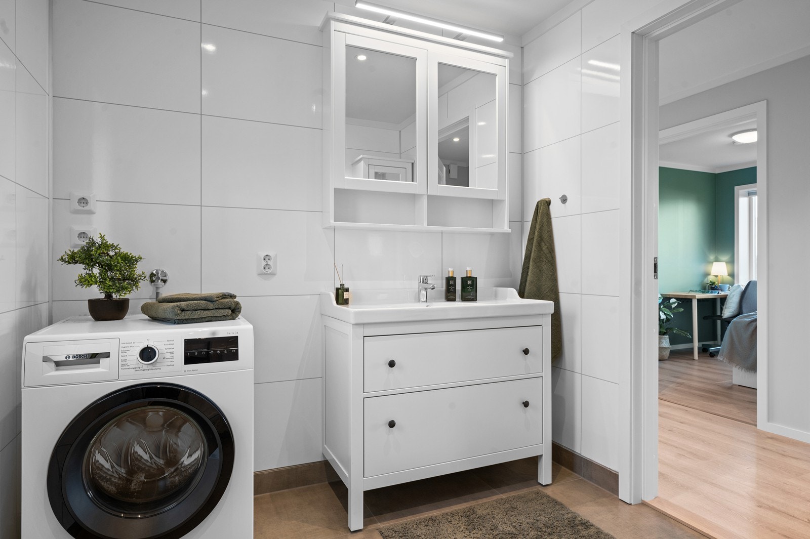 Badet har opplegg for vaskemaskin, og er innredet med servant, toalett, dusjhjørne og speilskap for praktisk oppbevaring. Galleribilde