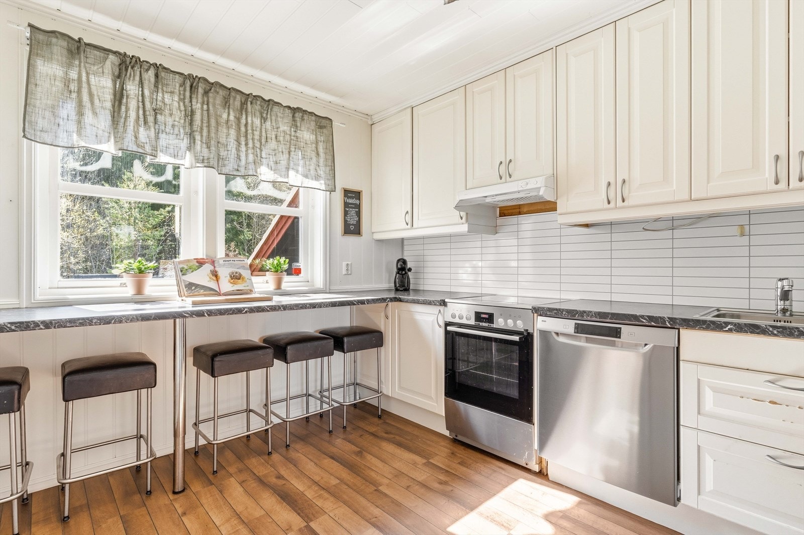 Videre er kjøkkenet utstyrt med frittstående oppvaskmaskin, komfyr med platetopp og frittstående kjøl/fryseskap. Galleribilde