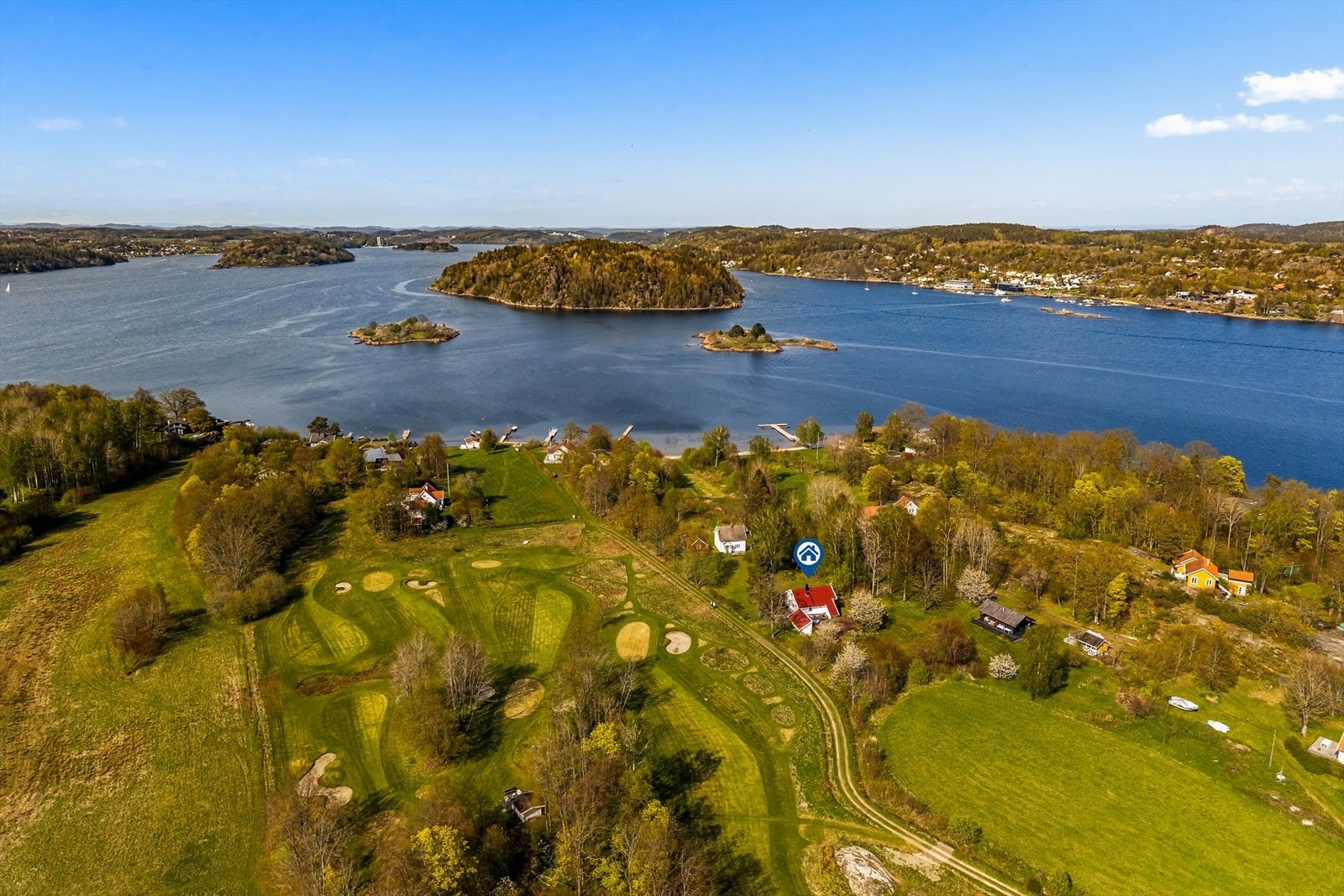 Luftfoto som viser hyttas beliggenhet mellom golfbanen og sjøen. Galleribilde