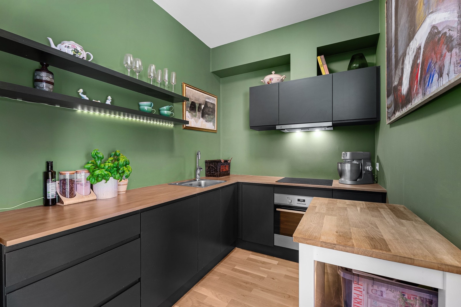 Moderne stilfult kjøkken med god benkeplass kombinert med åpne hyller, skuffer og overskap. Skap er malt i fargen Studio Green fra Farrow&Ball Galleribilde