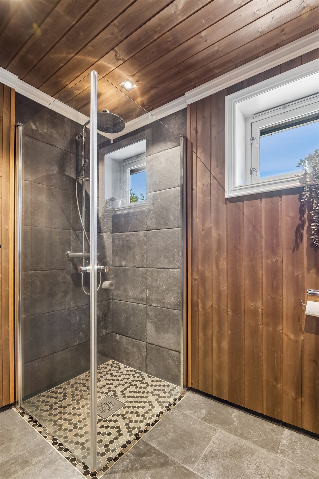 Badet har dusjhjørne med glassdører, servant og toalett. Galleribilde
