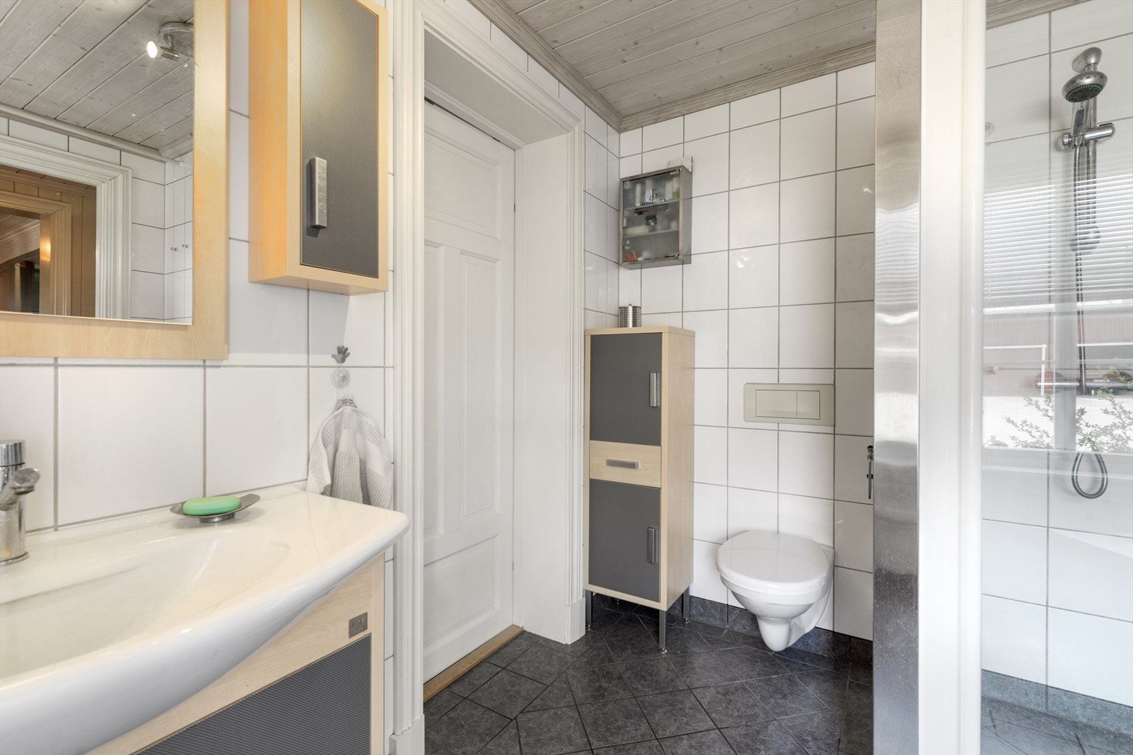 På badet er det vegghengt toalett, servant i skapinnredning og dusjhjørne med vegg i glassbyggerstein og glassdør. Galleribilde
