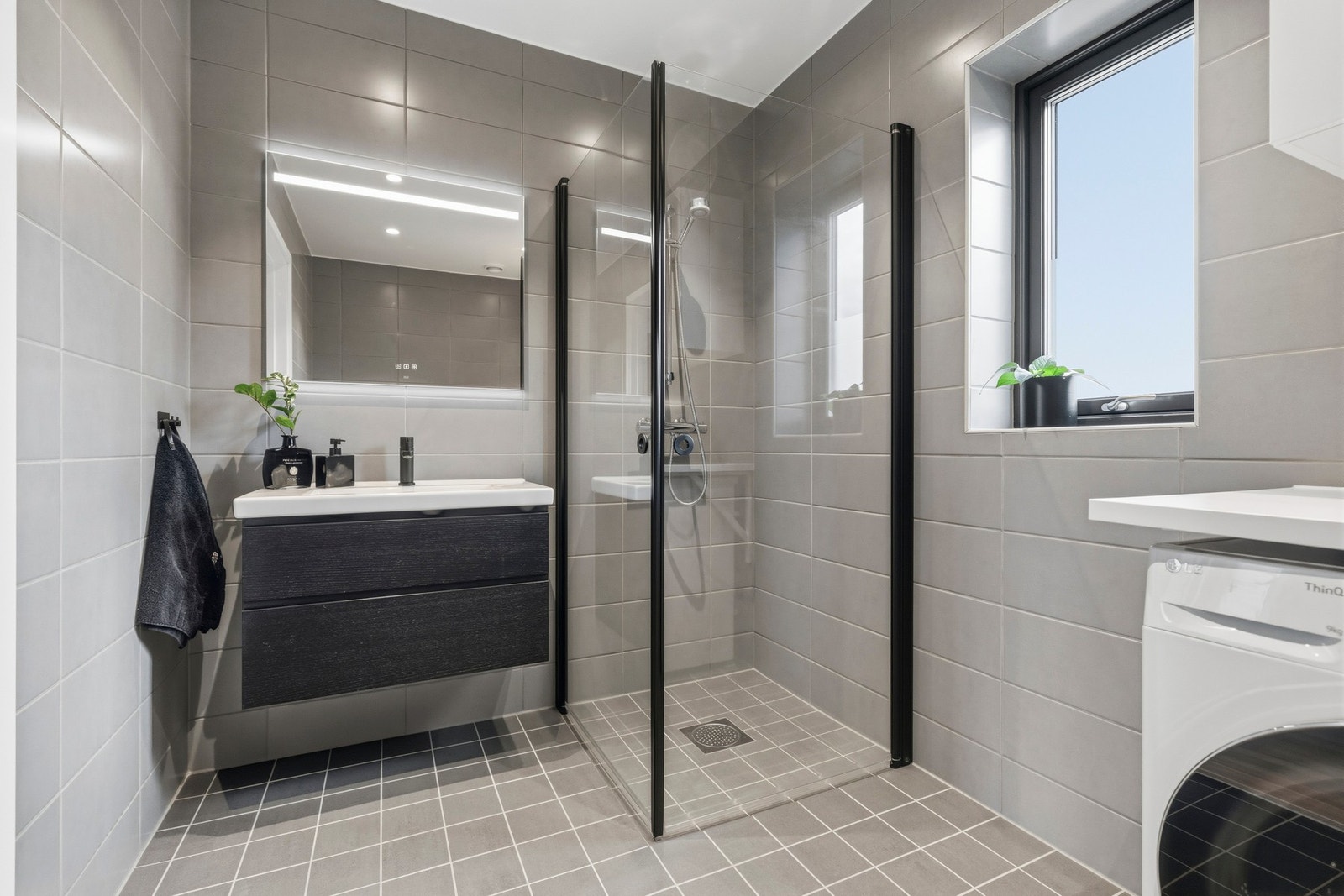 Badet har flislagte overflater, dusjløsning med glassvegger og moderne baderomsinnredning. Galleribilde