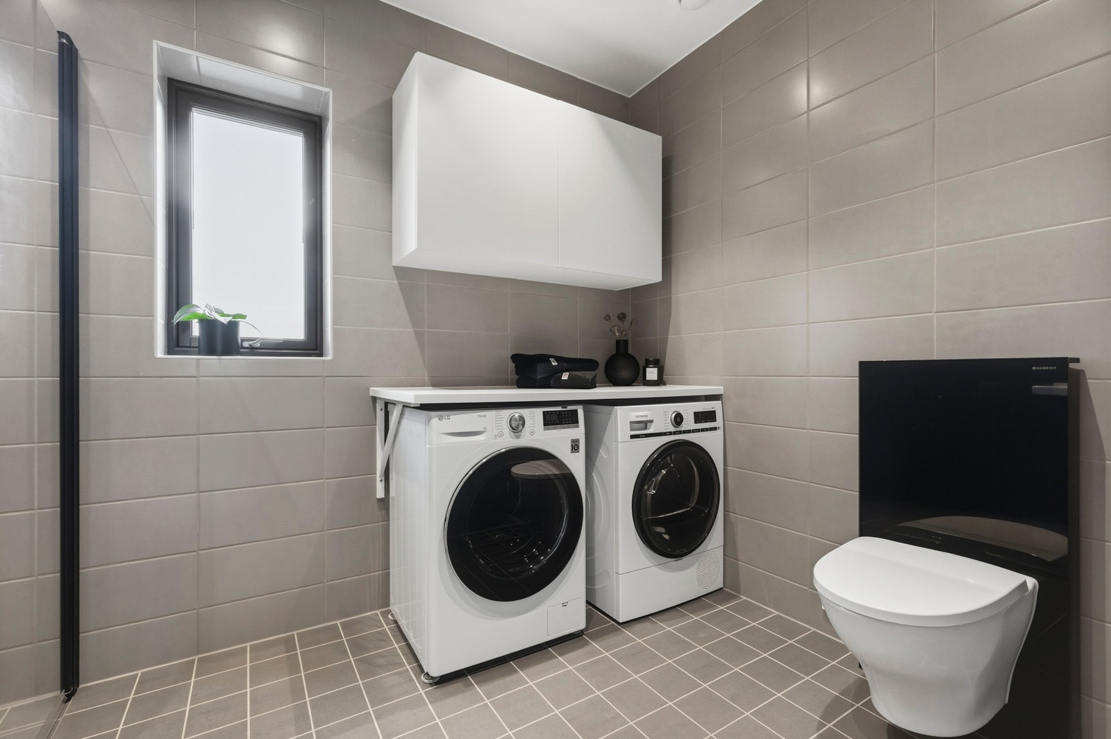 Badet er innredet med vegghengt toalett, opplegg for vaskemaskin og tørketrommel samt gode oppbevaringsmuligheter. Galleribilde