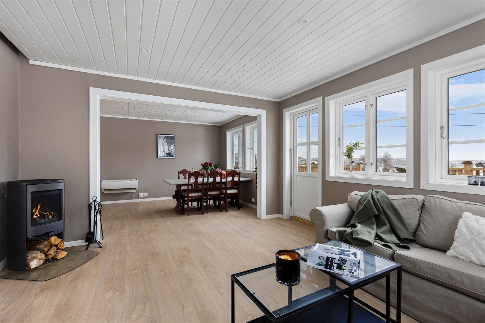 Boligen fremstår moderne og har overflater i tidsriktige farger og bred 1-stavs laminat på gulv i oppholdsrommet Galleribilde