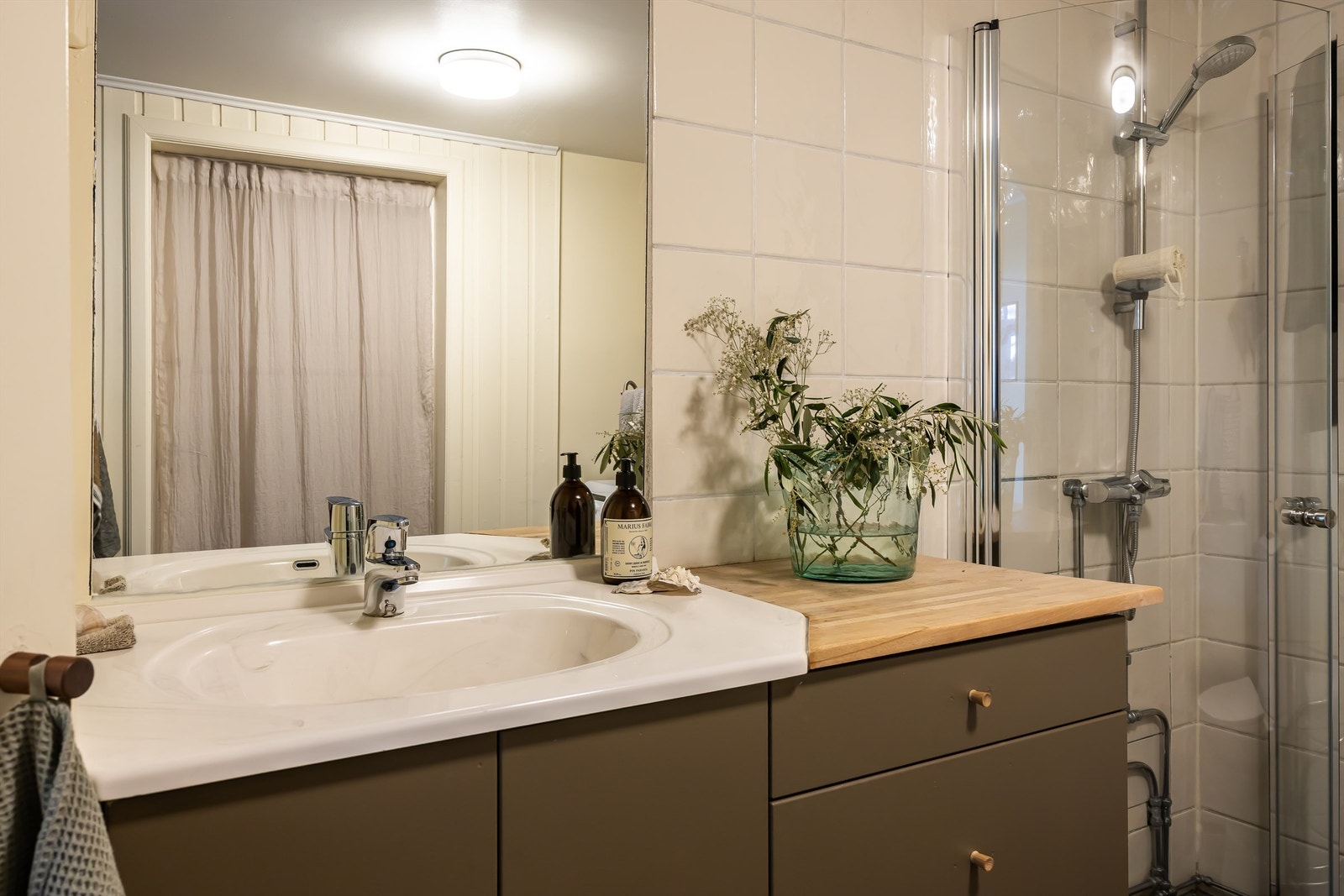 Badet er innredet med servant m/servantskuffer- og skap, gulvstående toalett, dusjhjørne med glassvegger og opplegg for vaskemaskin. Galleribilde