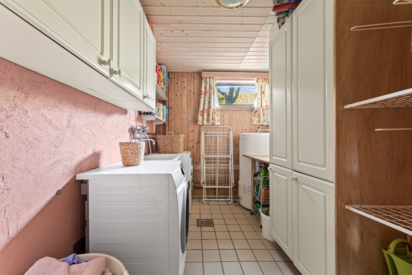 Kjelleren har et praktisk separat vaskerom med fliser på gulvet, og en innredning bestående av benkeskap og veggskap med profilerte fronter, skyllekum i plast og opplegg for vaskemaskin. Galleribilde