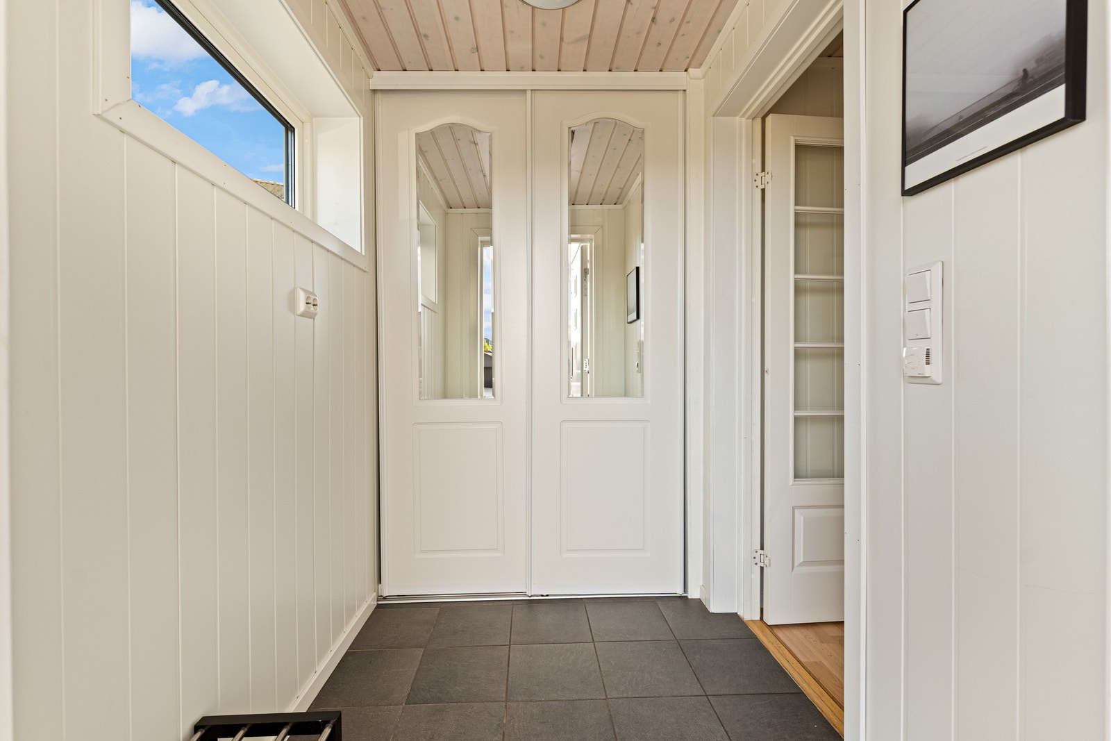 Entréen har flislagt gulv med gulvvarme og en praktisk skyvedørsgarderobe med gode oppbevaringsmuligheter. Galleribilde