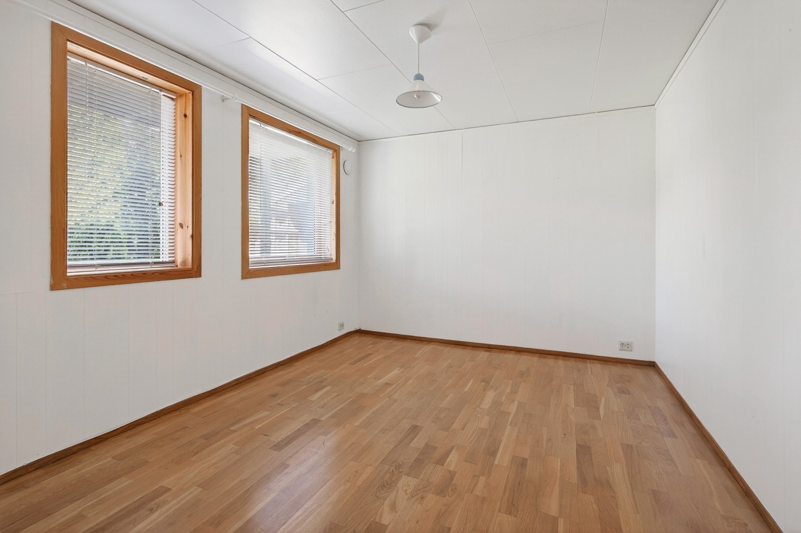 Kjellerstue (evt. soverom) med parkettgulv og malt panel Galleribilde