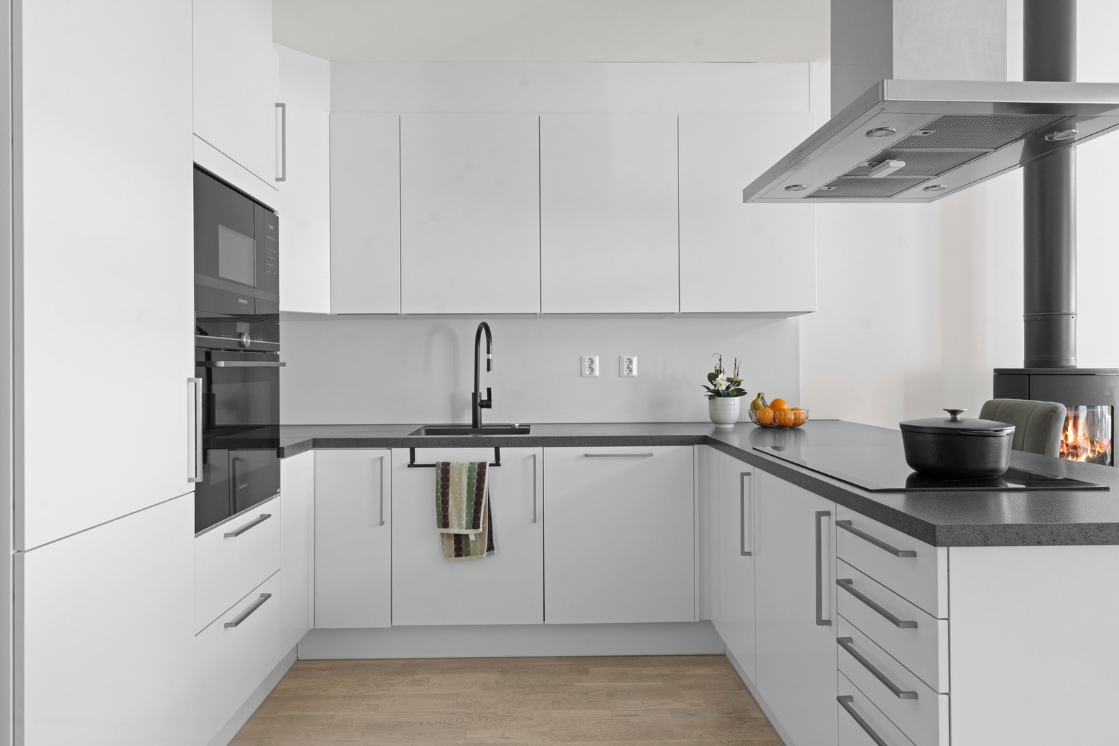 Stilrent kjøkken med gjennomgående moderne uttrykk og solide materialvalg. Kvalitetshvitevarer fra Bosch er integrert på en elegant måte, kombinert med rikelig skapplass, gode arbeidsflater og en helhet som vitner om høy standard og gjennomtenkt design. Galleribilde