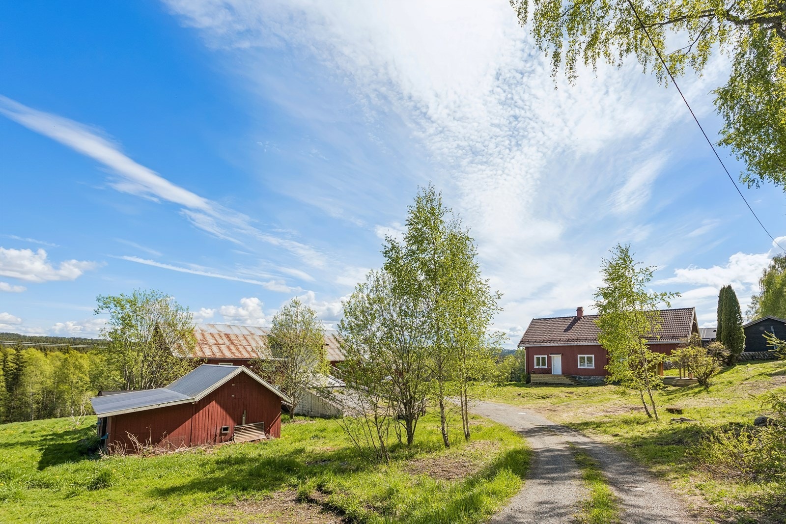 Landlig beliggende småbruk med tun, låve og fritt utsyn over omkringliggende jorder og skogsområder. Galleribilde