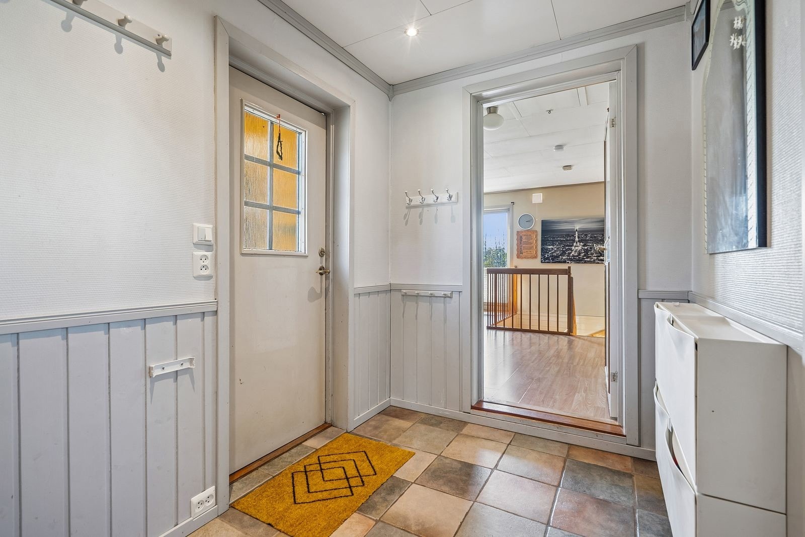 Innbydende entre, flislagt gulv og tidløst fargevalg på vegger.