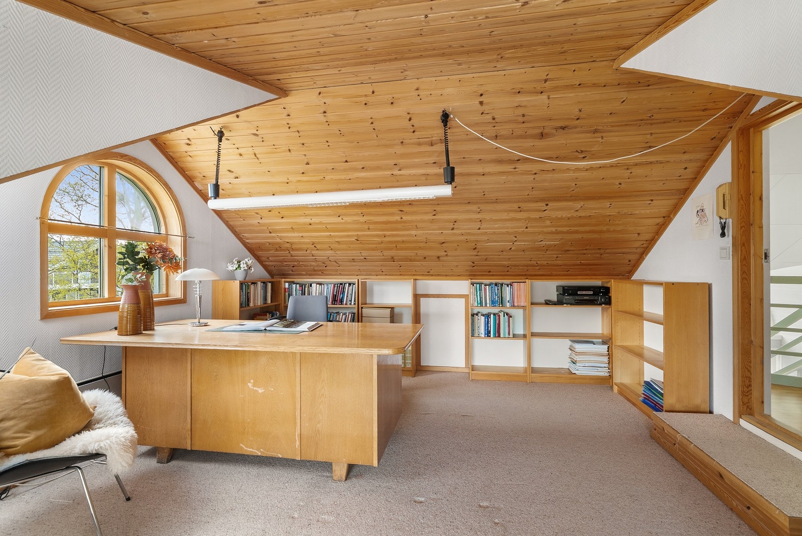 Kontor på loftet med teppe på gulv, malt strie på vegger og panel i tak. Galleribilde