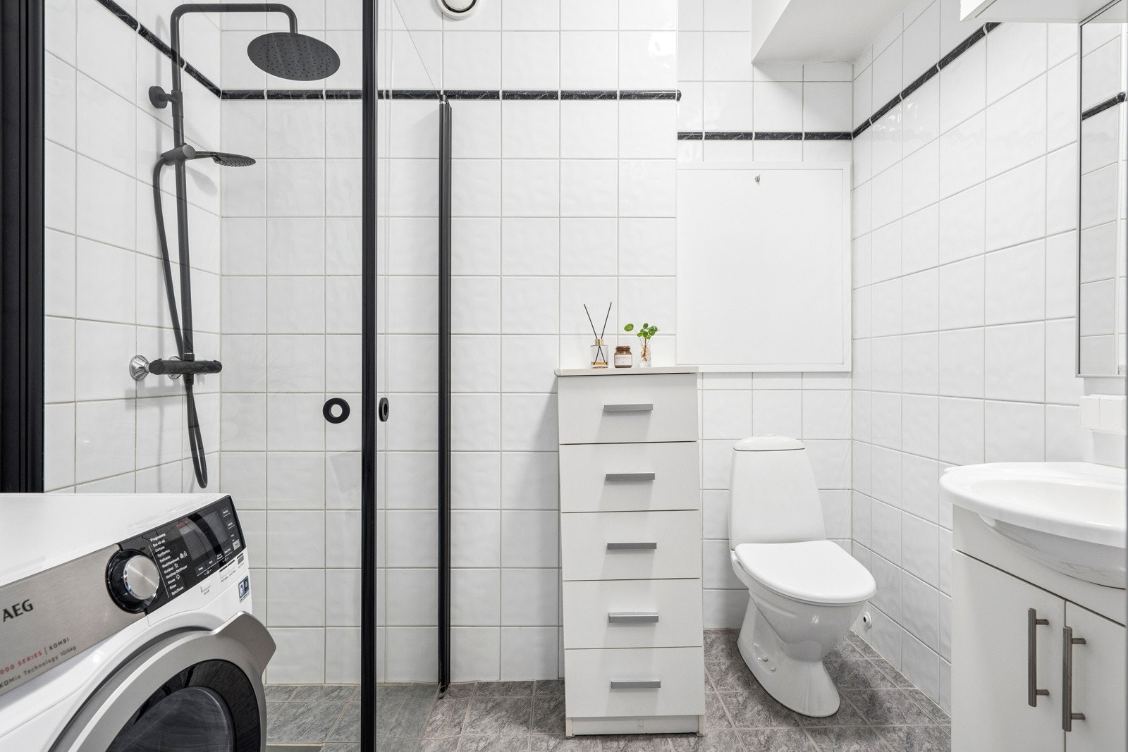 Flislagt bad med gulvvarme, dusjhjørne og opplegg for vaskemaskin.