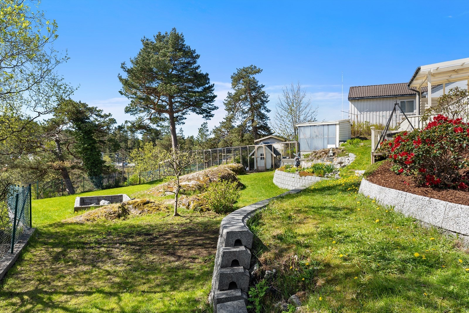 Tomten er pent opparbeidet med plen, støttemurer, inngjerdet hønsehus og diverse beplantning. Galleribilde