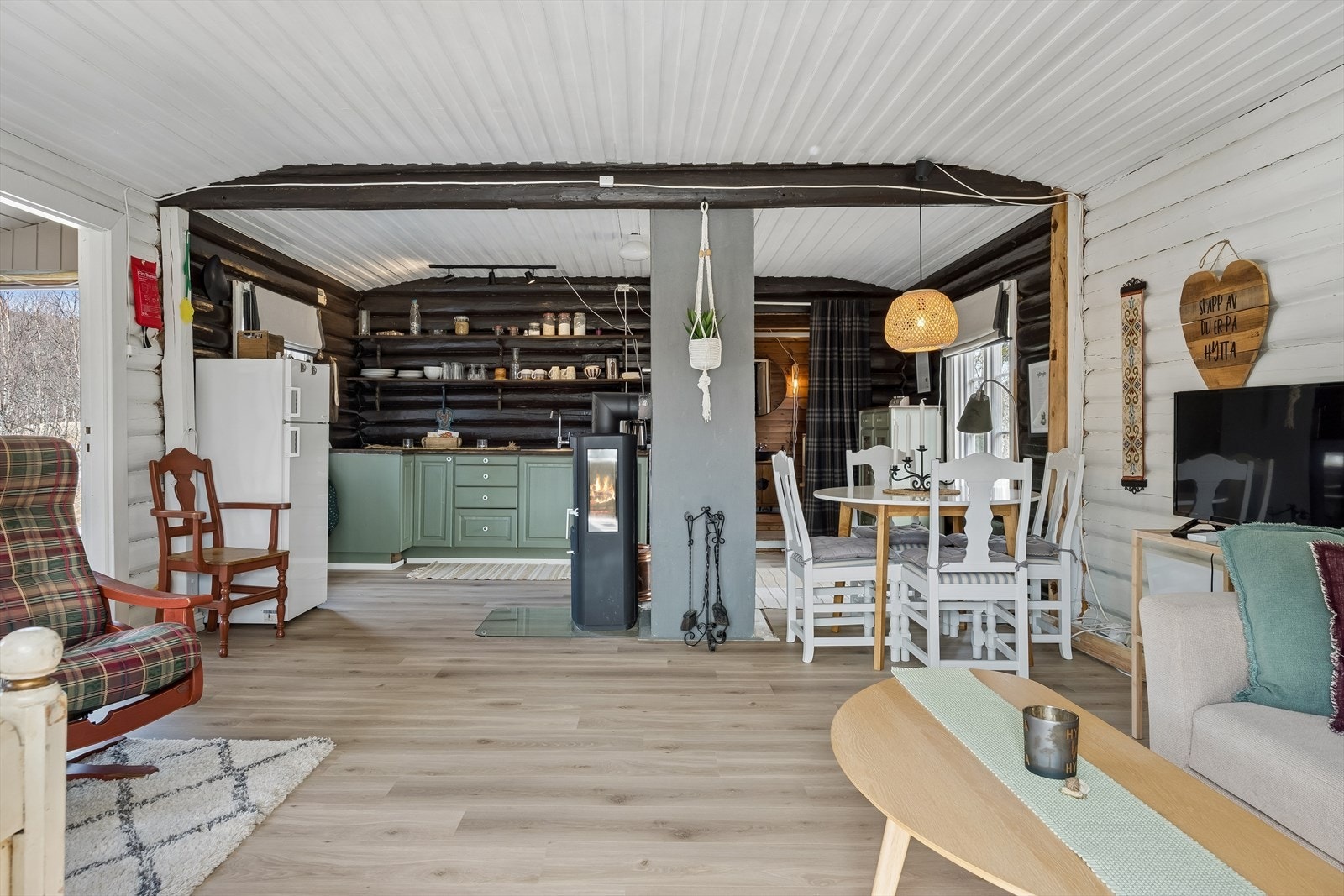 Stue og kjøkken utgjør et sosialt allrom, hvor originale tømmervegger møter moderne komfort. Galleribilde