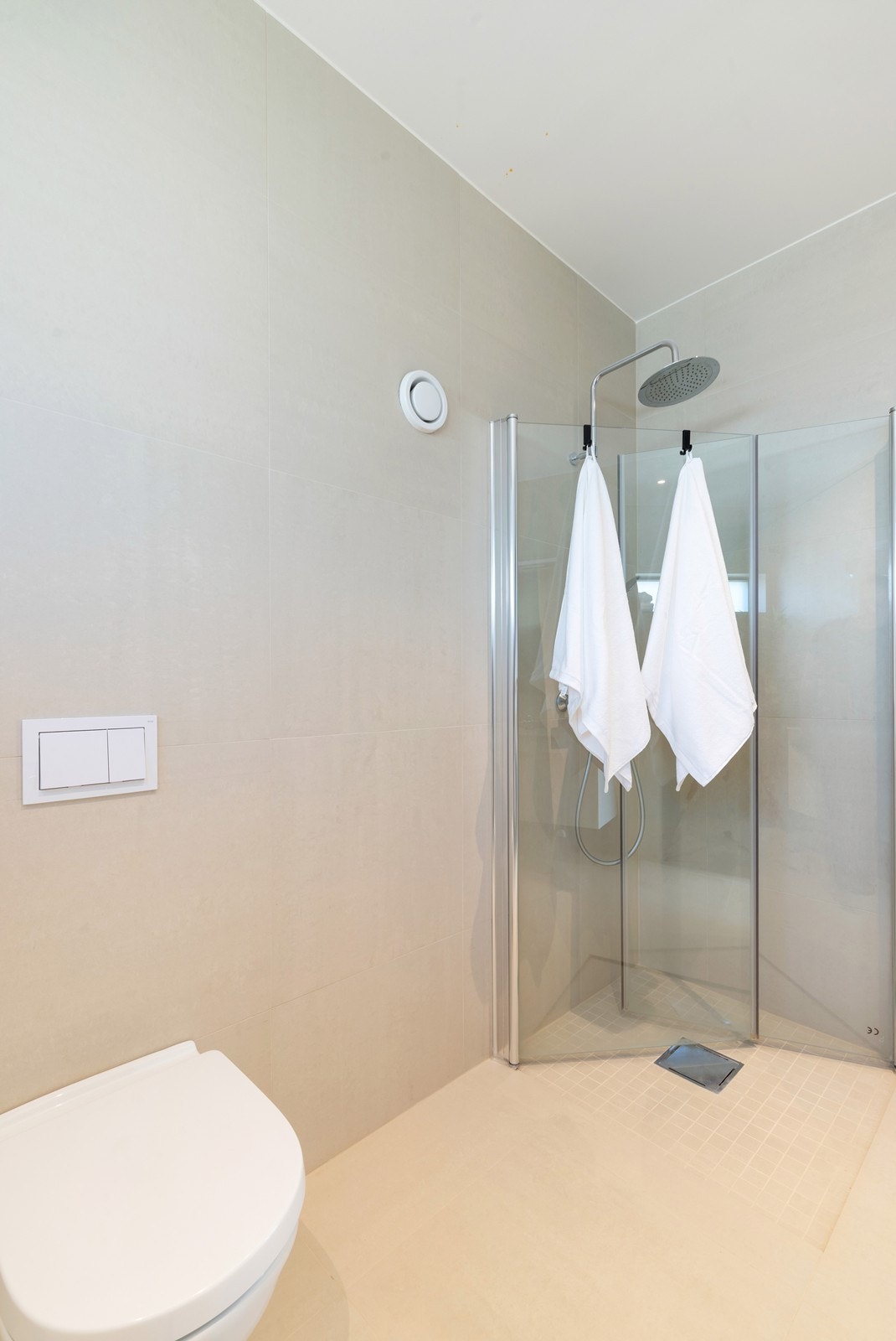 Lekkert flislagt bad/wc med varme i gulv, dusjhjørne, vegghengt toalett og servant med baderomsinnredning. Galleribilde