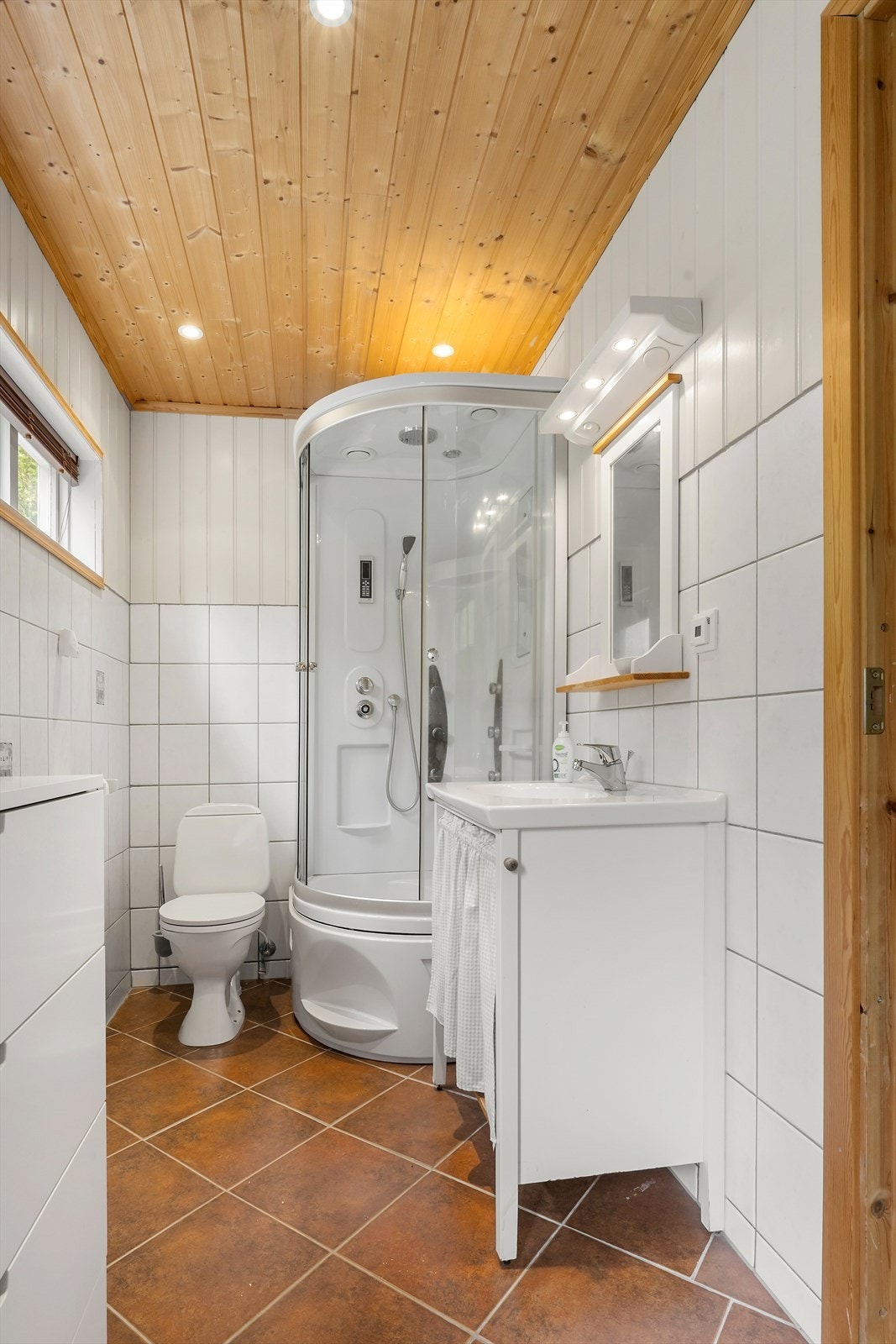 Badet er innreidd med dusjkabinett, servant og toalett. Badet har fliser på golvet med varme. Galleribilde