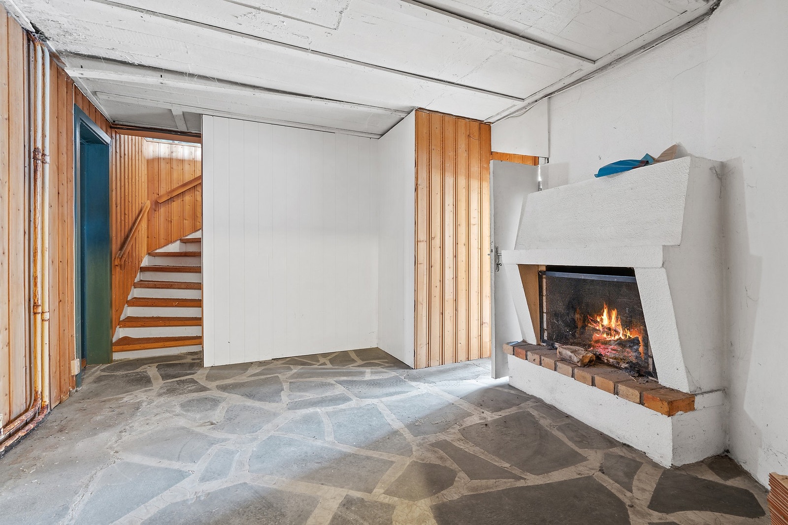 Rommet har vegger med trepanel og trappeforbindelse opp til hovedetasjen. Galleribilde