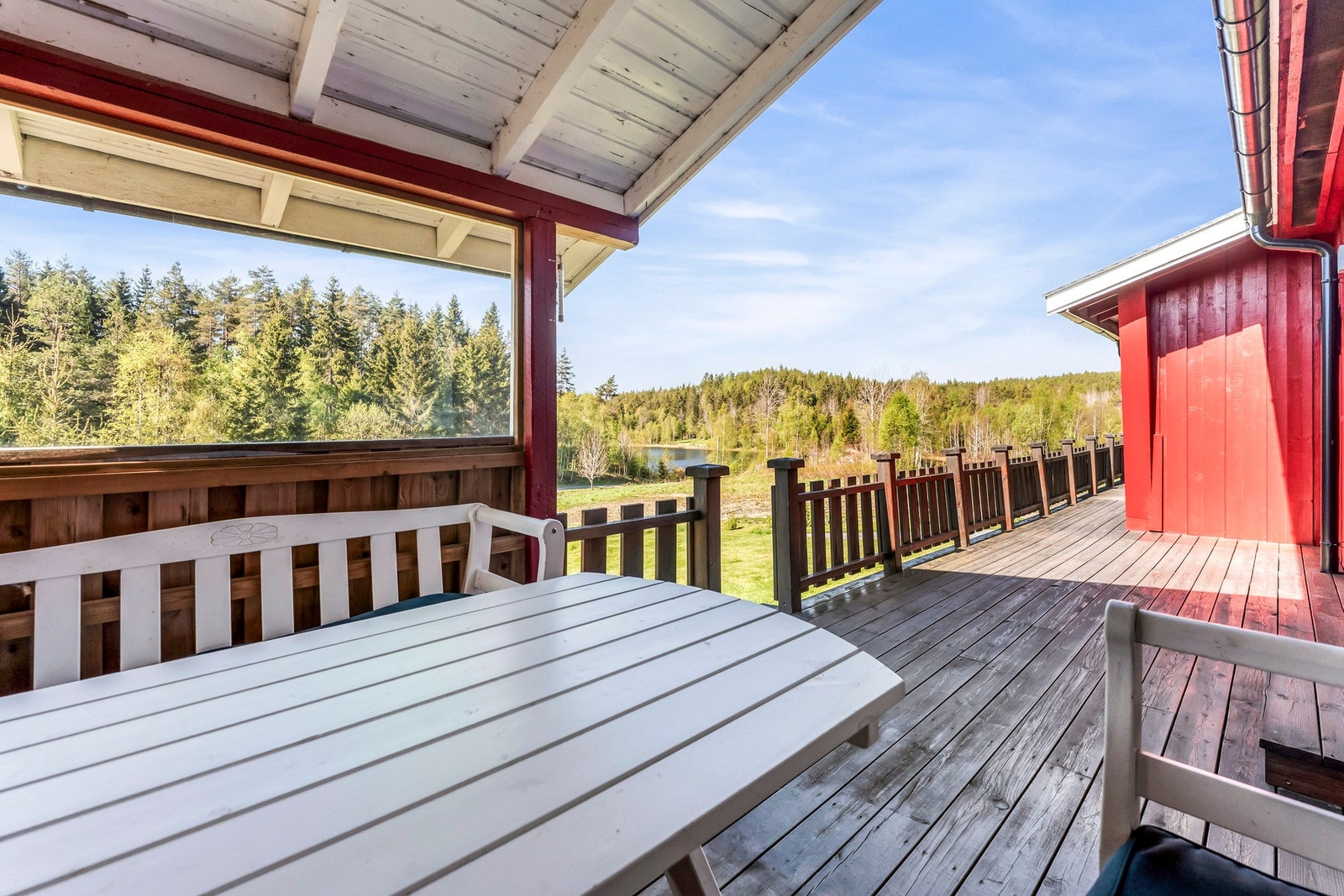 Stor terrasse med overbygg og utsikt mot skog og åser. Galleribilde