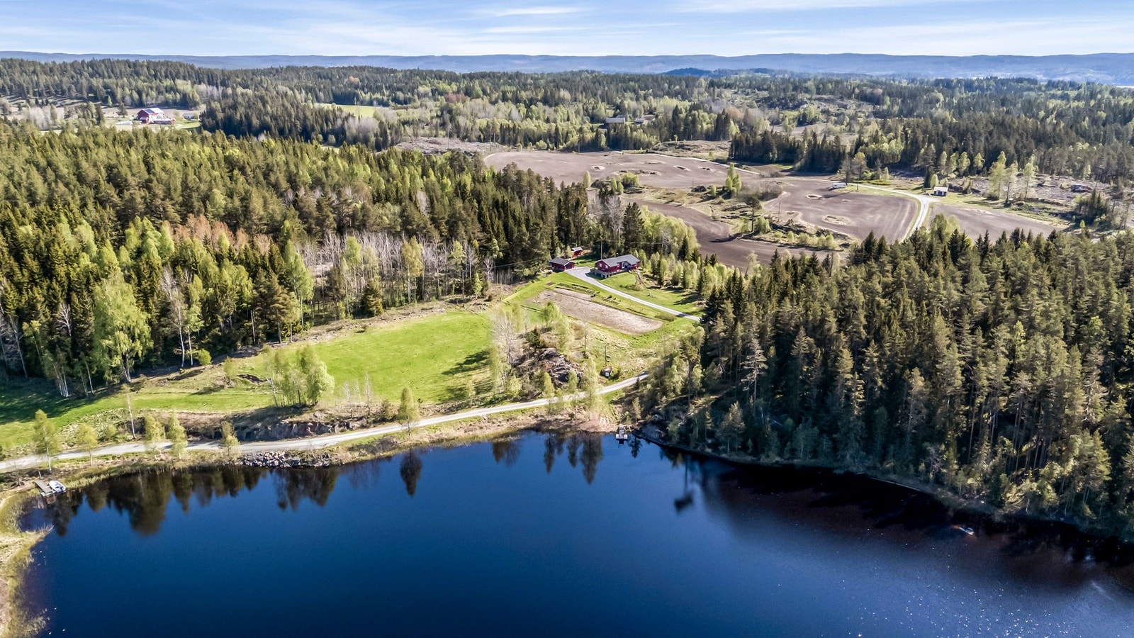 Eiendommen ligger i naturskjønne omgivelser med skog, åkerlandskap og en innsjø i nærheten. Galleribilde