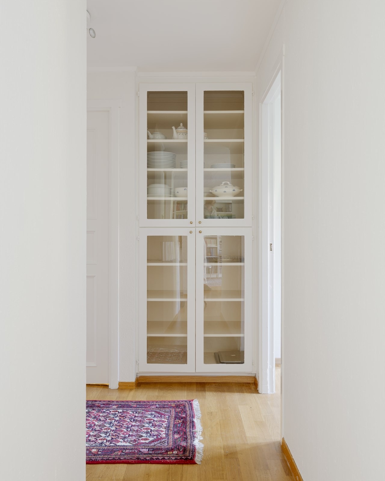 Et plassbygget vitrineskap i gangen gir elegant og praktisk oppbevaring. Galleribilde