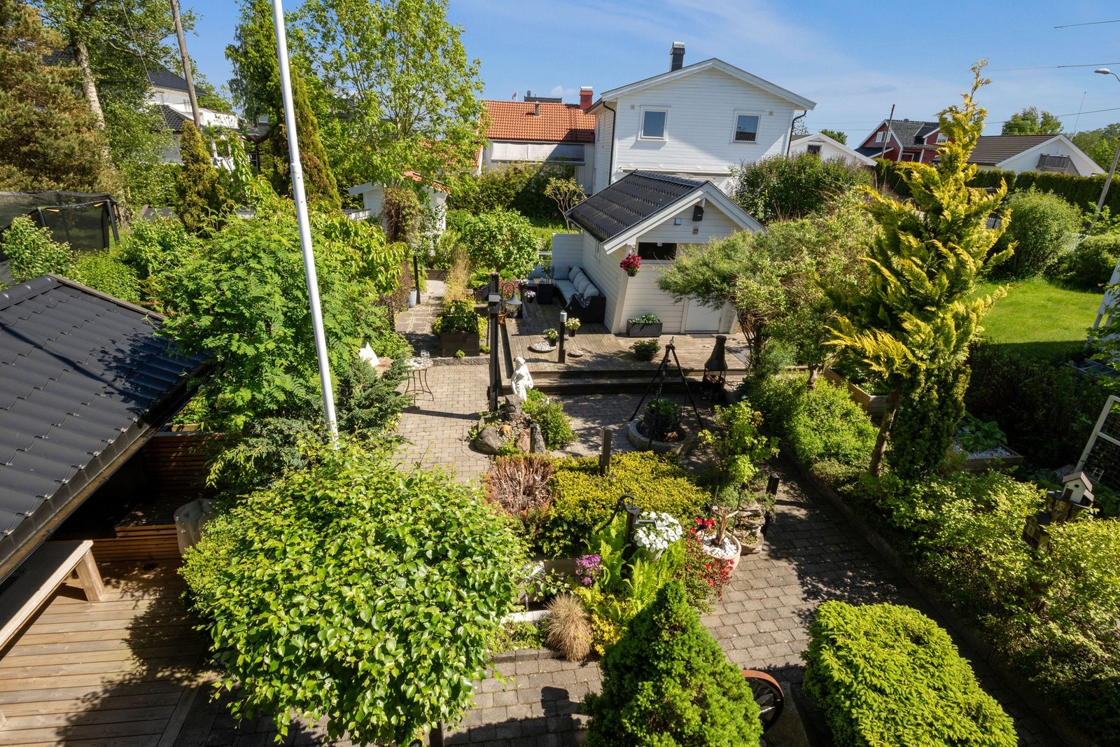 Innbydende hage med frodig beplantning og overbygget utestue Galleribilde