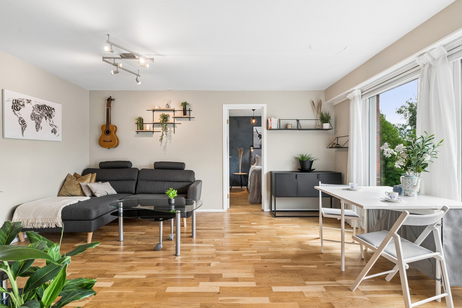 Lys og romslig stue med parkett på gulv og malte veggflater som gir leiligheten et hyggelig og innbydende preg. Galleribilde