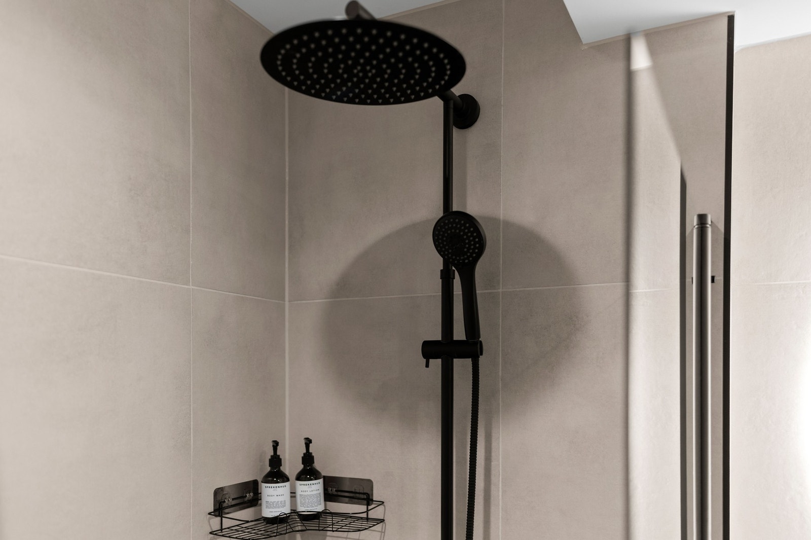 Badet er innredet med veggmontert toalett, servantinnredning, speil med intregrert belysning, dusjnisje og opplegg for vaskemaskin Galleribilde