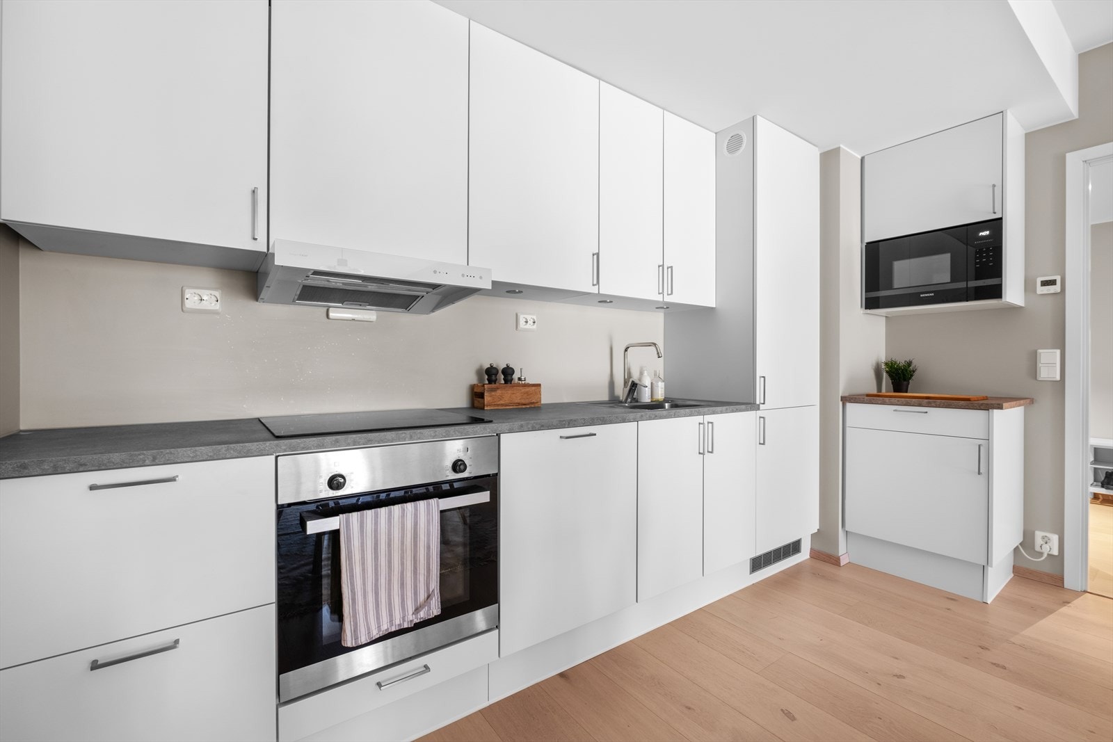 Kjøkkenet er utvidet med 60 cm ekstra underskap, overskap med integrert mikrobølgeovn og benkeplate i samme modell som det eksisterende kjøkkenet fra JKE Design. Galleribilde