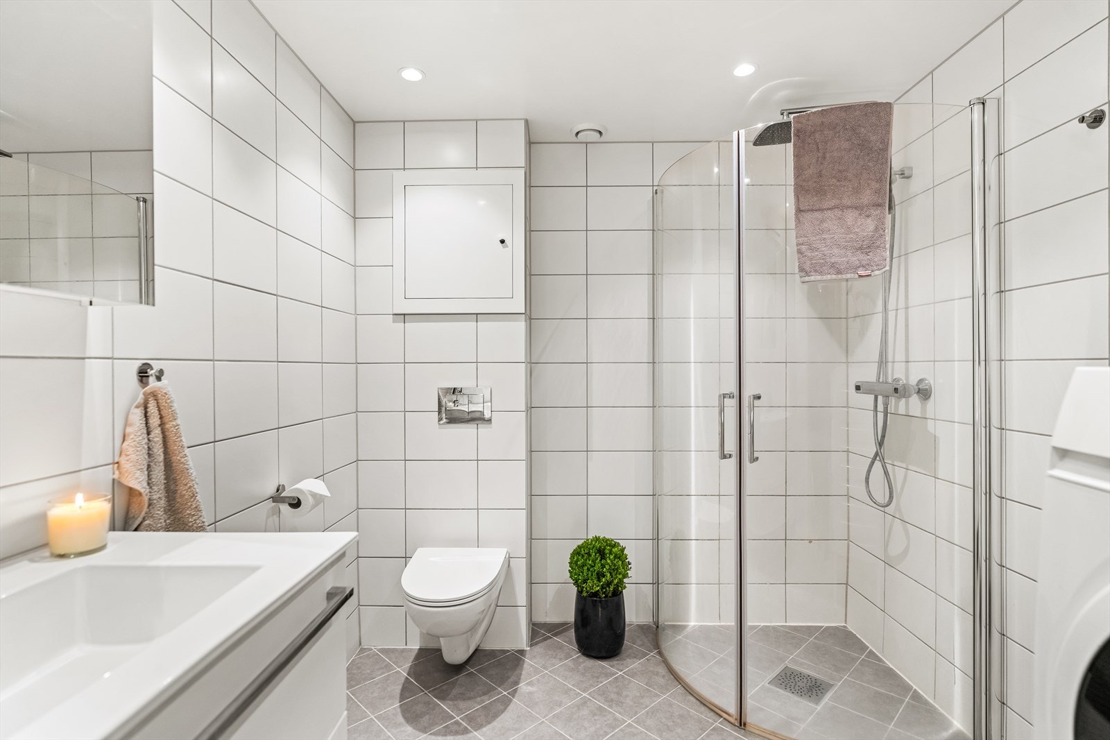 Badet er innredet meg vegghengt wc, innfellbare glassvegger, skap med glatte fronter, servant og opplegg for vaskemaskin/tørketrommel. Galleribilde