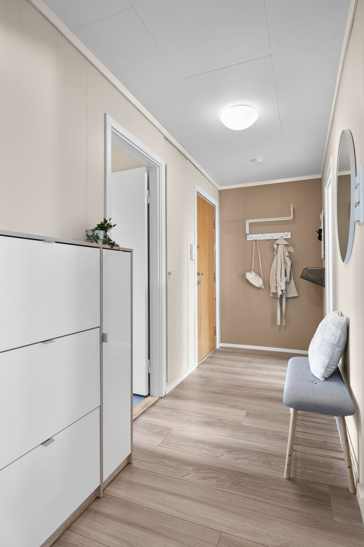 Leiligheten har en pen entré med lyse veggflater og laminat på gulvet. Galleribilde