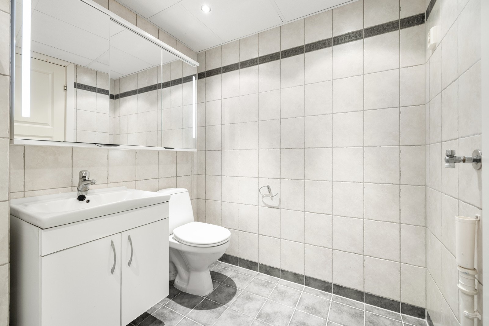 Badet har opplegg for vaskemaskin, servantinnredning og speilskap med belysning. Galleribilde